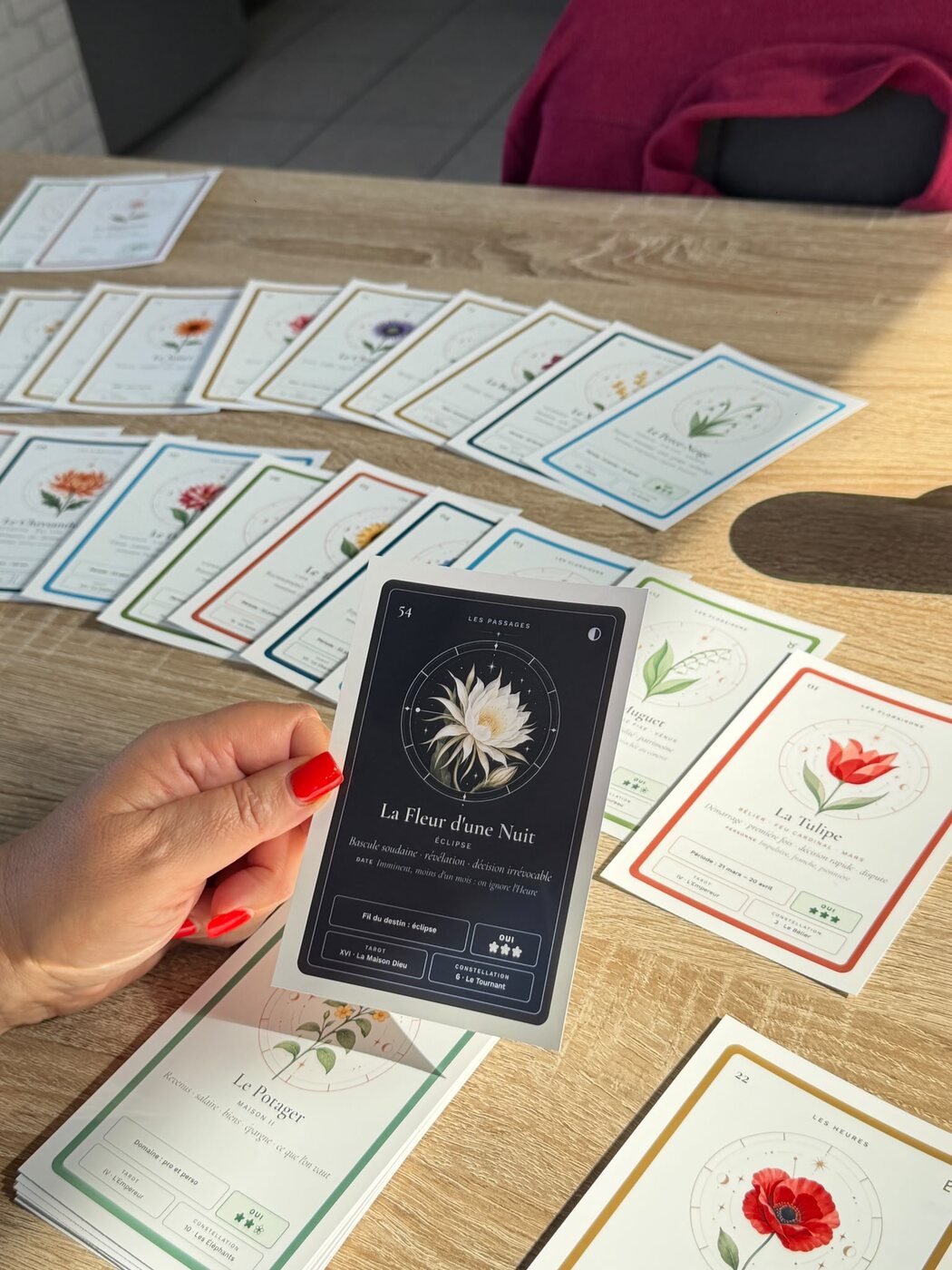 La carte La Fleur d'une Nuit du prototype Isayan tenue en main au-dessus d'un tirage étalé.